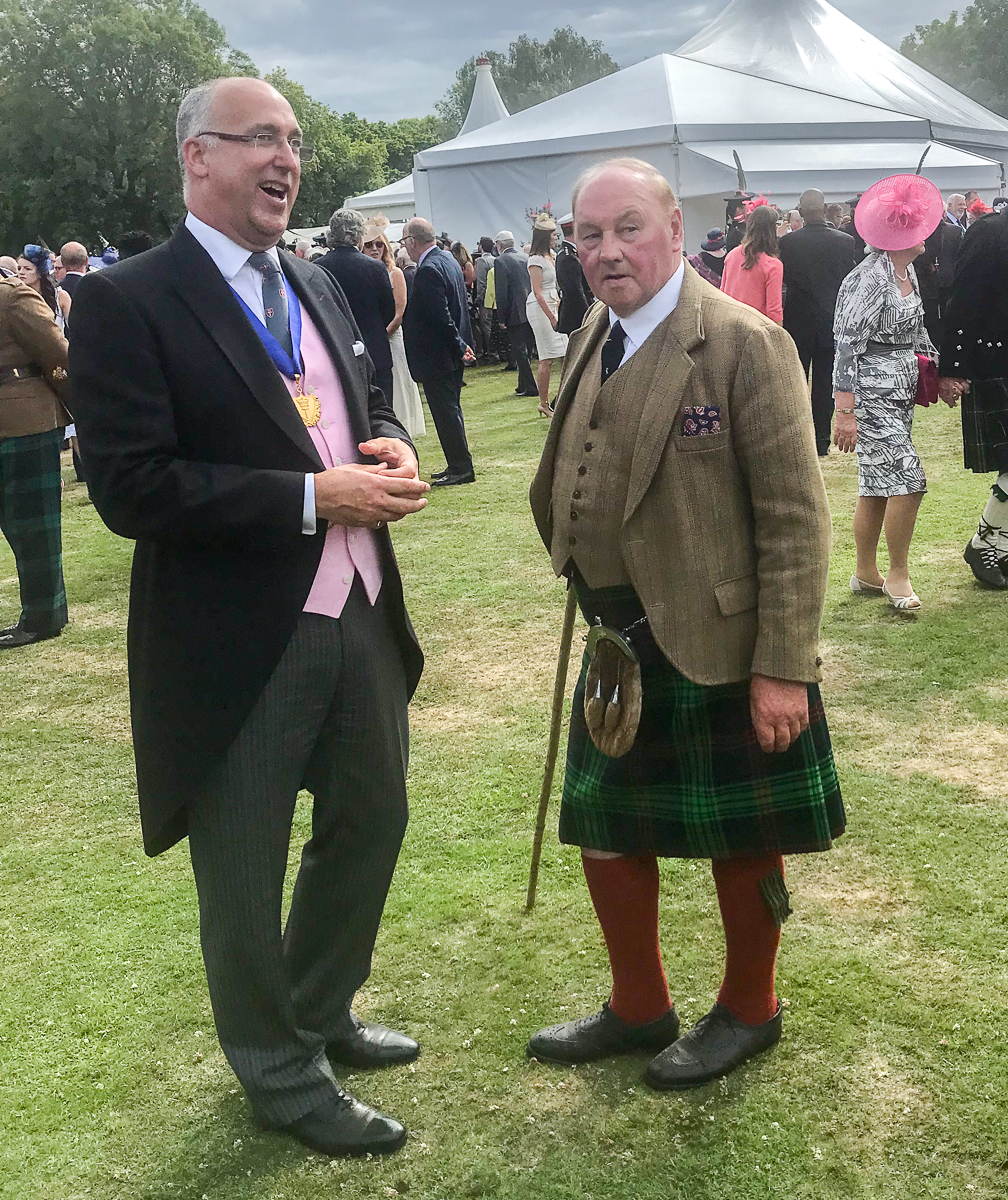 Teo men in formal dress chatting at garden party